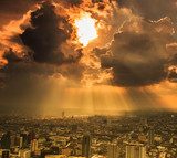 Rays of light shining through dark clouds in the Bangkok city 