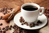 Coffee beans and cup of coffee on table on brown background 