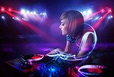 Disc jockey girl playing music with light beam effects on stage 