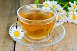 Herbal chamomile tea in a glass cup on a board 