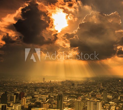 Rays of light shining through dark clouds in the Bangkok city