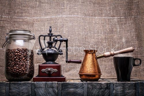 Coffee beans in a glass jar, coffee grinder, a coffee pot, a mug