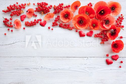 Red poppies, heart and berries on a wooden background