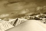 Sepia off-piste snowy slope and cloudy mountains 