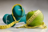 healthy apple, measuring tape and dumbbells