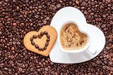 Heart shaped cup and cookie on coffee beans background