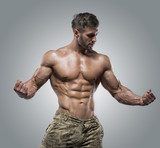 Muscular athlete bodybuilder man on a gray background