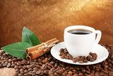 Coffee beans and cup of coffee on table on brown background 