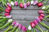 Frame of fresh tulips arranged on old wooden background 