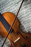 Wertvolle alte Geige mit Bogen liegt auf einem Notenblatt 