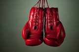 Boxing gloves hanging from laces on a grey background 