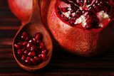 Ripe pomegranate seed in wooden spoon on bamboo mat background 
