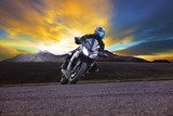 young man riding motorcycle in asphalt road curve with rural and 