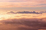 Orange sunset with mountain peaks above clouds