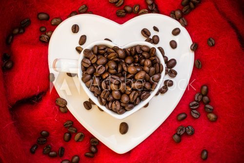 Heart shaped cup with coffee beans on red