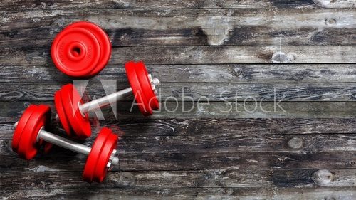 3D rendering of adjustable metallic red dumbbells, on wooden background with copy-space