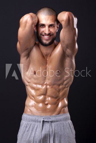 Smiling fit man flexing the abdominal on black background