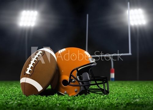 Football Ball and Helmet On Grass under Spotlights