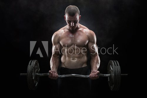Young muscular man lifting weights over dark background
