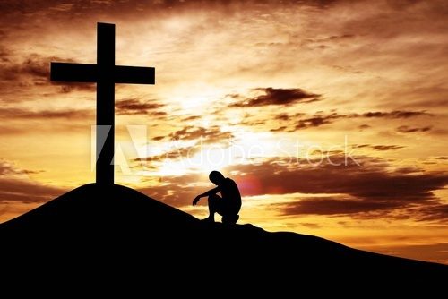 Man sitting desperately under the cross