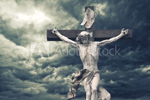 Crucifixion. Christian cross with Jesus Christ statue over storm