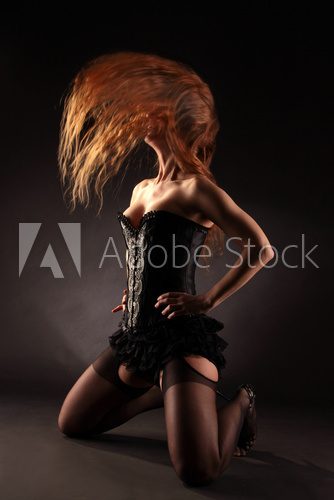 Eine Frau in schwarzer Korsage schüttelt langes Haar