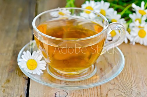 Herbal chamomile tea in a glass cup on a board