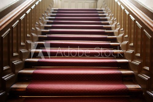Empty wooden staircase with red carpet