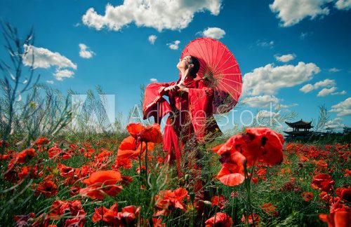 Woman in red clothes with chinese umbrella in the poppy field