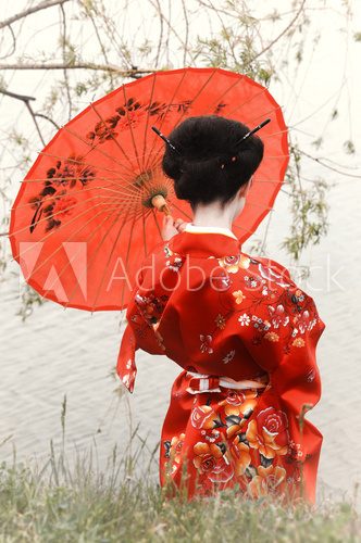 Geisha with red umbrella at the riverside (back view)