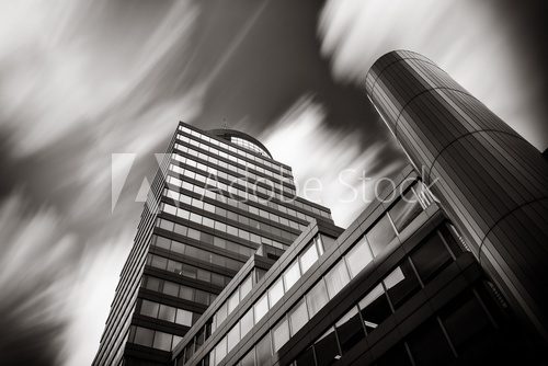 Long time exposure of clouds over modern office building. Black and white picture.