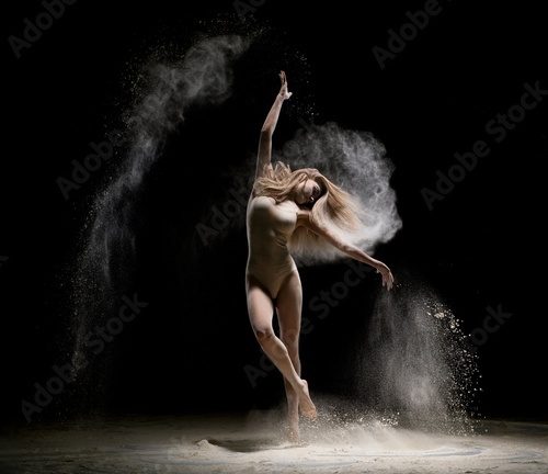 Gorgeous girl dancing in dust in the dark