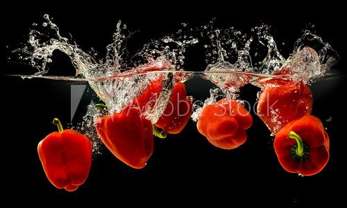 Group of bell pepper falling in water with splash on black background