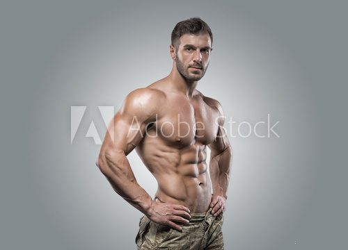 Muscular athlete bodybuilder man on a gray background