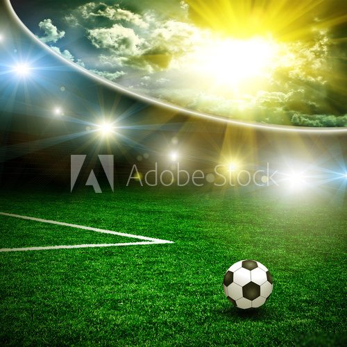 Soccer ball on the green field and lightning