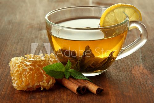 Transparent cup of green tea with honey and cinnamon